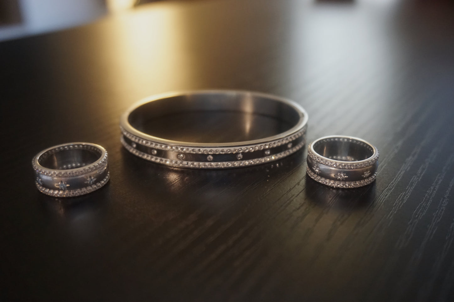Three silver rings on a dark wooden surface