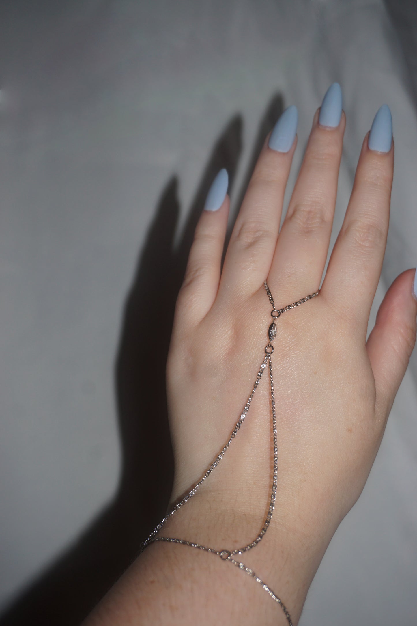 Hand wearing a delicate chain bracelet on a neutral background