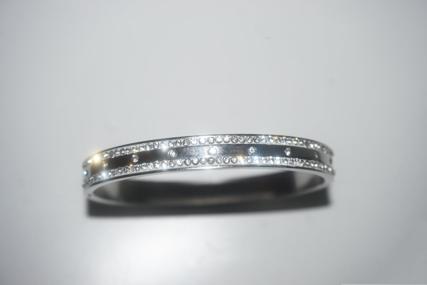 Silver ring with embedded diamonds on a light gray background