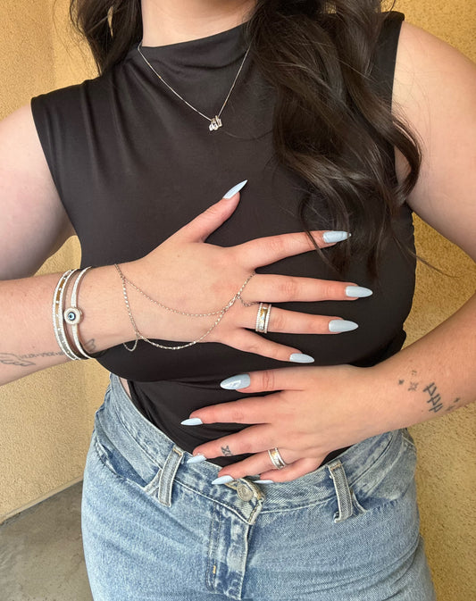 Person wearing a black sleeveless top and blue jeans with a neutral background