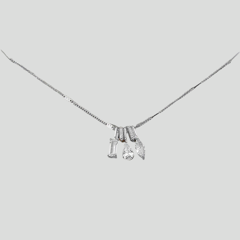 Silver necklace with three charms on a light gray background