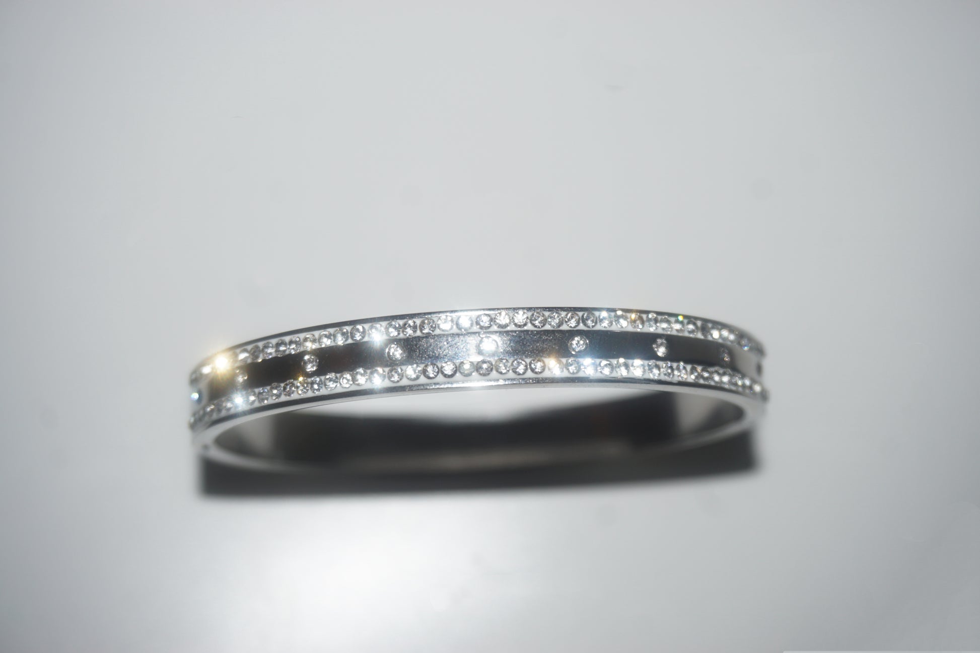 Silver ring with embedded diamonds on a light gray background